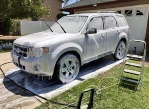 a small SUV foamed up with auto soap