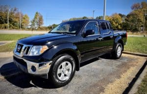 a clean Nissan black truck parked by the grass