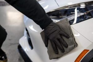 a man wiping a white sports car after being polished