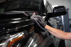 a man wiping a black truck with a towel