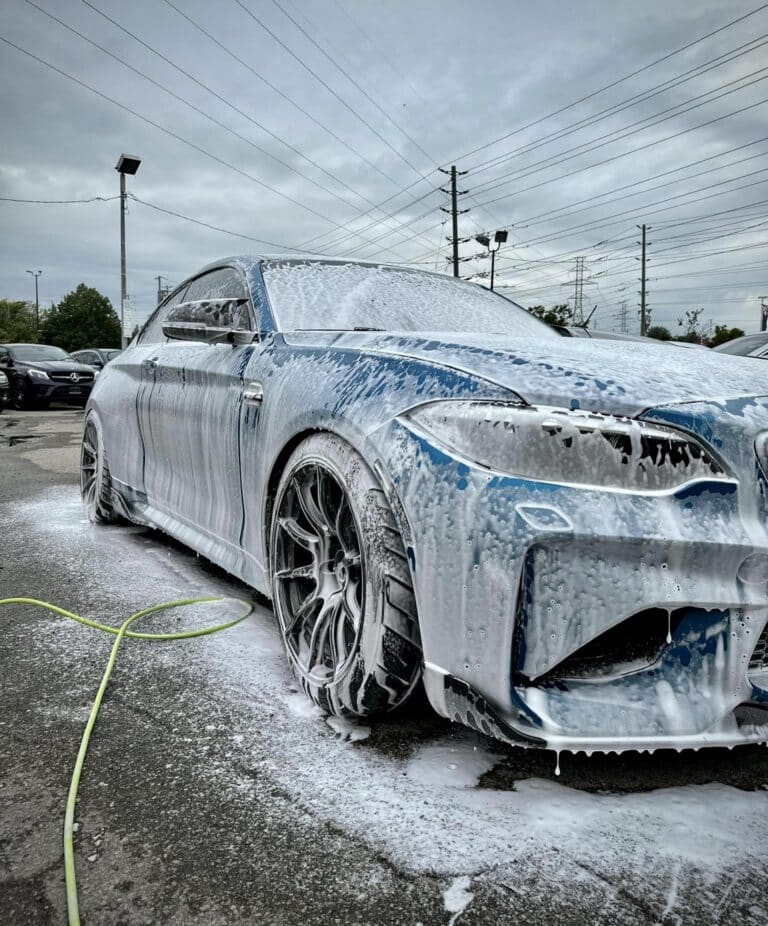 a vehicle that's foamed up with car soap and a water hose