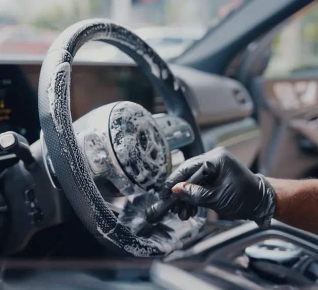 a black steering wheel being cleaned with a brush