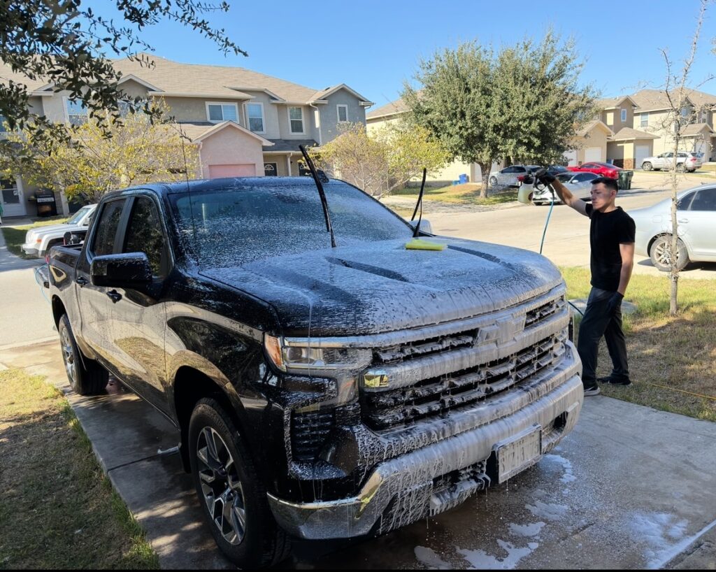 Chris covering a Chevy pickup truck in thick foam using a foam cannon during a mobile detail