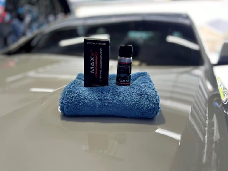 A couple bottles of ceramic coating sitting on the top of a hood of a car